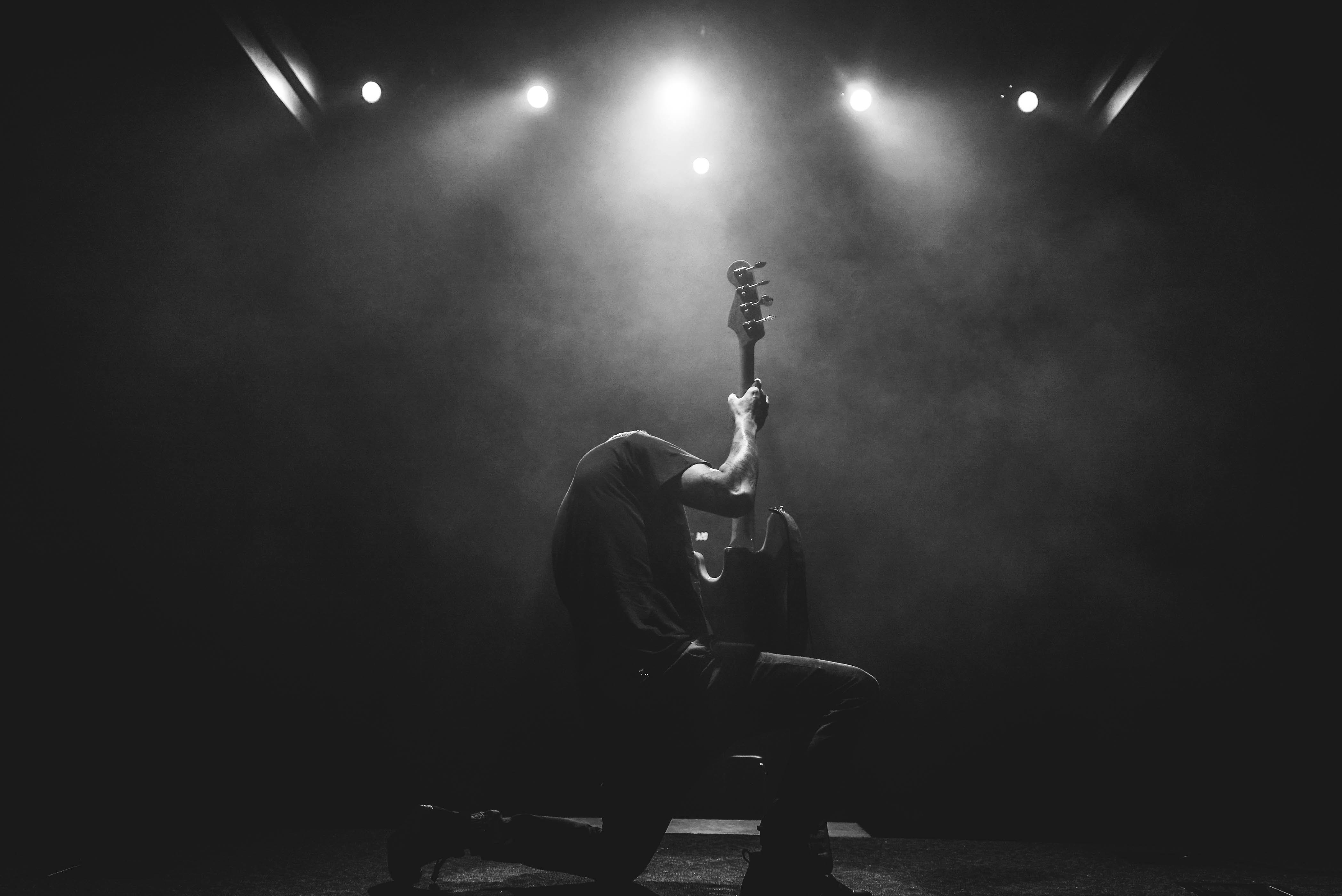 Курят и слушают рок. Гитарист на сцене. Рок гитарист. Гитарист в темноте. Сцена в темноте.